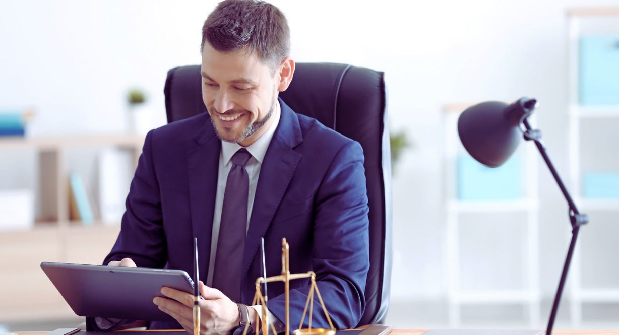 Avocat travaillant sur une tablette a son bureau avec une balance de la justice