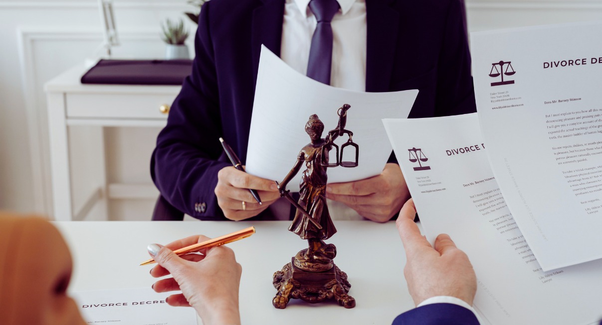 Avocat tenant un acte de divorce avec une statue de la Justice sur le bureau