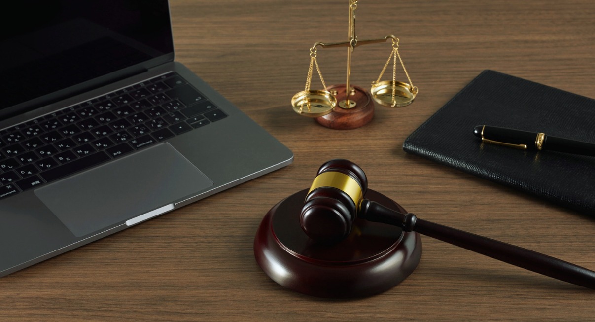 Bureau d'avocat avec marteau de justice, balance dorée et ordinateur portable sur table en bois