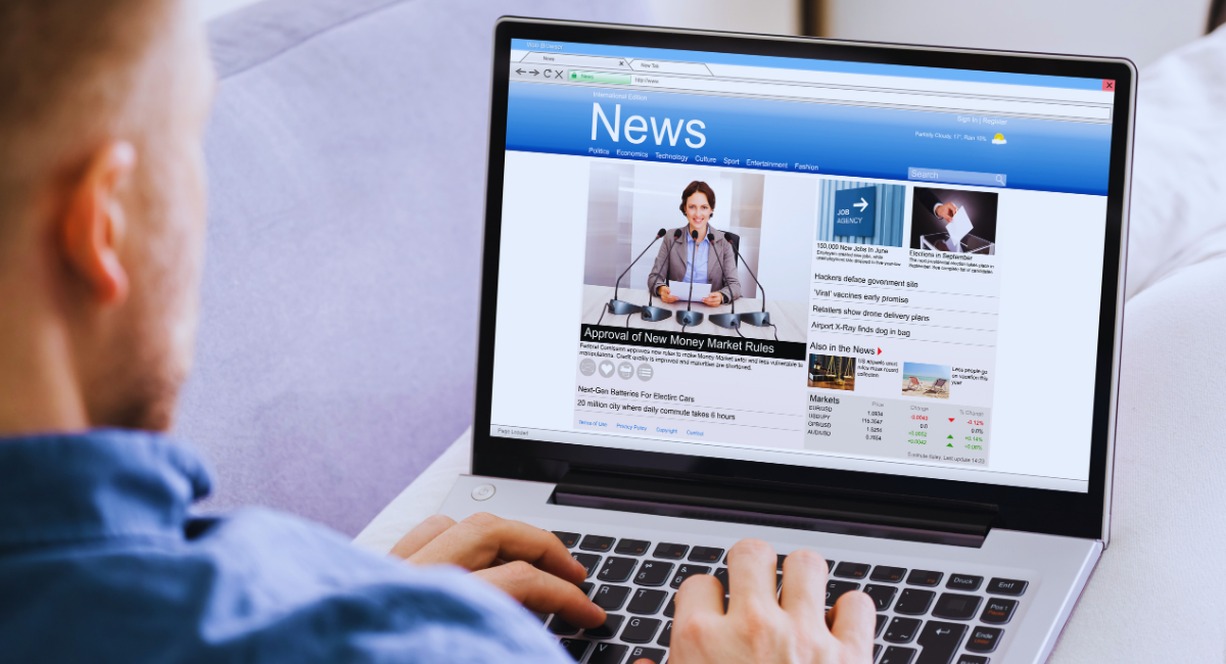 Personne lisant un magazine d'actualite en ligne sur l'ecran d'un ordinateur portable