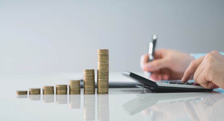Empilements de pièces de monnaie en progression croissante avec une calculatrice illustrant le calcul du salaire brut net