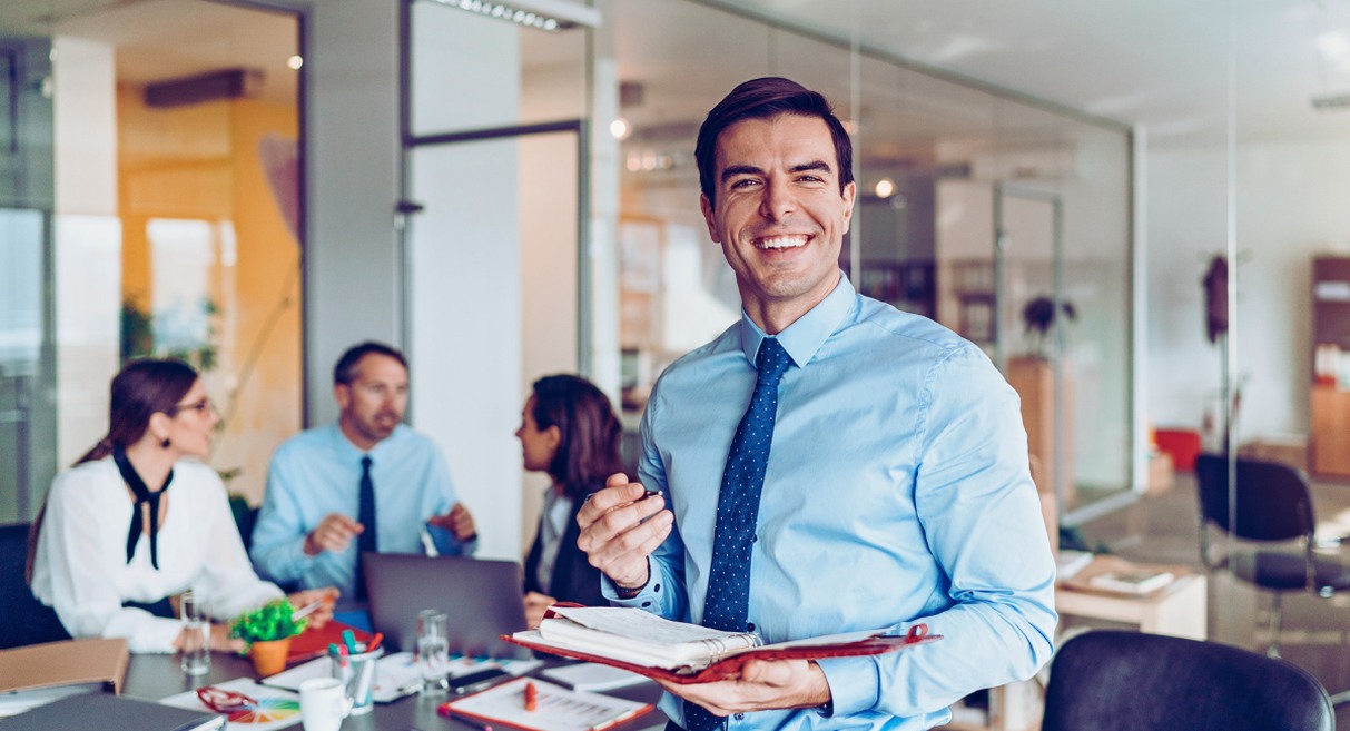 Manager souriant devant son equipe en reunion, illustrant un management bienveillant