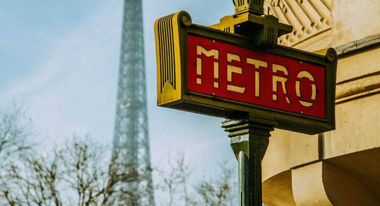 Enseigne rouge du métro parisien avec la Tour Eiffel en arrière-plan
