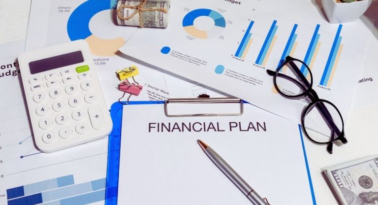 Bureau avec un plan financier sur porte-bloc, une calculatrice, des graphiques budgetaires et une paire de lunettes